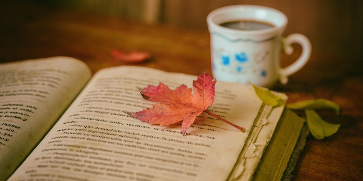 A person engrossed in reading at a coffee shop, symbolizing the flexible and self-paced nature of online learning.